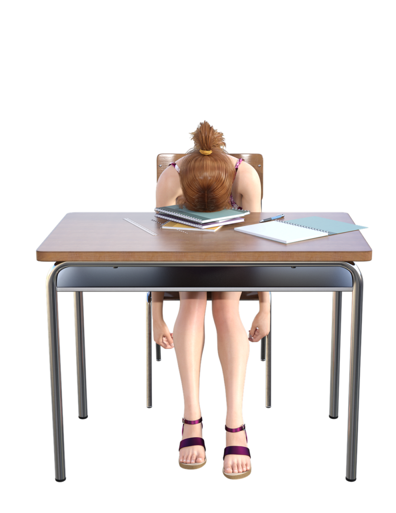 Teen girl with head down on desk appearing to be depressed.